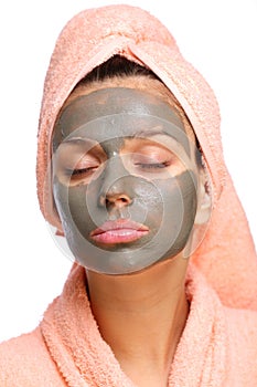 Close face of young woman with a mud mask on it.