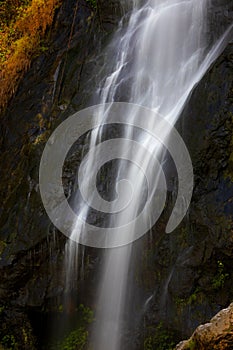 Close focus on smooth flowing water from high rock waterfall