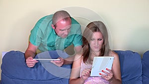Close friends man and woman using personal tablet computer sitting on sofa