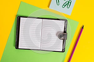 Close front view private dark leather locked diary with striped paper sheet marker notepad clips colored background