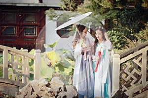 Close girlfriends bestie in Chinese traditional ancient costume in a garden