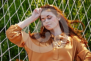 a close horizontal photo of a beautiful woman lying in a hammock with her eyes closed enjoying a rest.