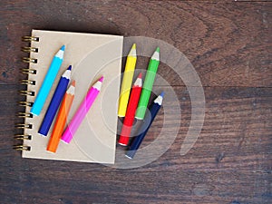 Close note book and color pencil on wooden background