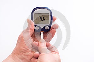 Close person checking blood sugar with glucometer and test strip at home