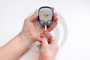 Close person checking blood sugar with glucometer and test strip at home