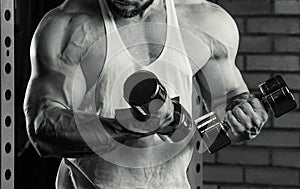 A close photo of arms of a bodybuilder who is doing biceps curls with dumbbells