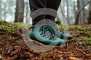 Close photo, feet in the boots of a tourist standing on the ground in the woods