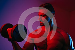 Close photo of a muscular man who is doing bicep curls under blue and red lights