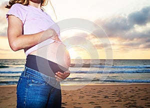 Close photo of pregnant woman belly over sunset