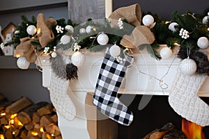 A close picture of beautifully decorated white Christmas socks hanging on fireplace waiting for presents. Christmas socks hanging