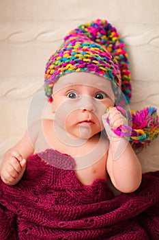 Close portrait of adorable baby in knitted funny gnome hat lies on his back