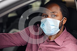 Close portrait of black ethnic man wearing medical mask in the car