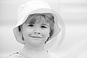 Close portrait of a boy with long hair in hat. Happy little child smiling. Adorable baby having fun. Carefree child