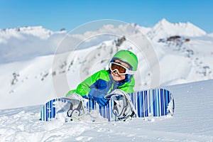 Close portrait of a boy with snowboard lay in snow