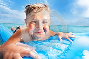Close portrait of a boy swim on matrass in the sea