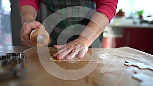 A close portrait of an elderly womans hand rolling out the cookie dough with a rolling pin. Christmas gingerbread cookie
