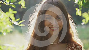 A close portrait of a girl with a bouquet of wildflowers in her hands. The girl looks at the camera and smiles. Beautiful