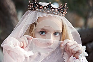 Close portrait of the girl enchantress in the crown with a face covered with a veil and charming big eyes