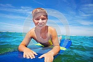 Close portrait of happy surfing boy on surfboard