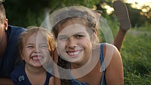 Close portrait of a large family with three children outdoor. Happy children and their parents are lying in the grass