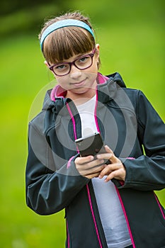 Close portrait Little girl with mobile phone. Little girl with standing and texting with the phone