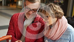 Close portrait of mature men and women browsing photos in a mobile phone. Pensioners are dressed in spring jackets and