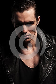Close portrait of rocker in leather jacket posing in dark