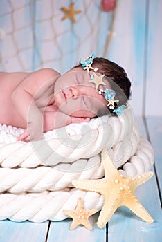 Close portrait of a sleeping newborn girl in the maritime hoop of starfish and pearls