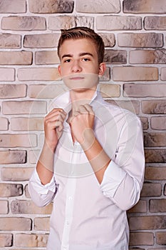 Close portrait of teenage boy in shirt near brick wall in studio