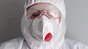 Close portrait of tired doctor in a medical protective mask, glasses and overalls