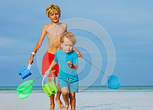 Close portrait of two boys on a beach with buckets and hoop-net