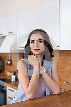 Close portrait of a young attractive elegant smiling woman in the kitchen behind the counter