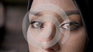 Close portrait of young muslim woman`s eyes looking at camera in hijab, sad and depressed expression