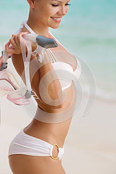 Close portrait of Young woman with wet skin and with a snorkeling equipment on sand and going to swim in clear ocean