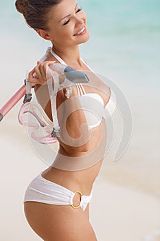 Close portrait of Young woman with wet skin and with a snorkeling equipment on sand and going to swim in clear ocean