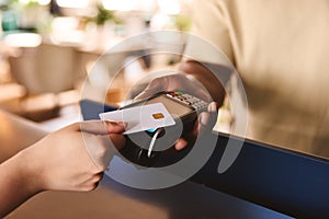 Close In Of Sales Assistant In Retail Shop With Customer Paying Using Contactless Payment Credit Card NFC