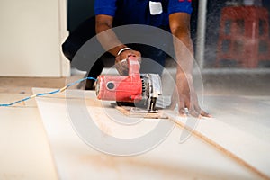 Close shot of carpenter or wood worker cutting wood by using circular saw machine at workplace - concept of hard wood