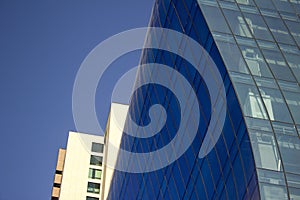 Close shot of a curved blue glass window wall of a modern and elegant corporative building.