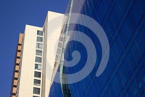 Close shot of a curved blue glass window wall of a modern and elegant corporative building, next to a yellowish classical one.