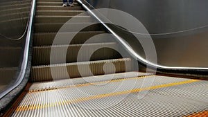 Close shot of electric escalator with parts of a person going downwards