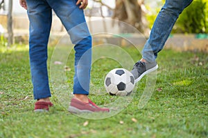 Close shot of father and son playing with football at park - concept of summer holidays, relationship and active