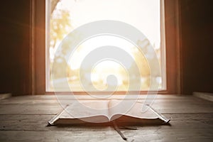 Close shot of holy bible on a wooden surface with the sun shining in the background