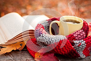 Close shot of open book and yellow tea mug with warm scarf