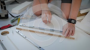 Close shot at the owner of the apartment hands, persons collects a table for his living room using a screwdriver, screws