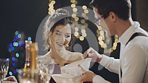 Close shot of portraits of young couple talking at table during holiday. Caucasian guy taking care of asian girl and