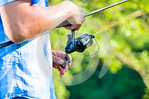 Close shot of sport fisherman reeling in line on fishing rod