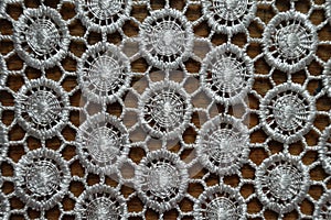 Close shot of white crochet lacy fabric on wood from above