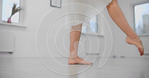 Close shot: woman dancer rehearses barefoot on the floor of the dance hall, ballet dancer, ballerina in the ballet