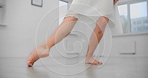 Close shot: woman dancer rehearses barefoot on the floor of the dance hall, ballet dancer, ballerina in the ballet