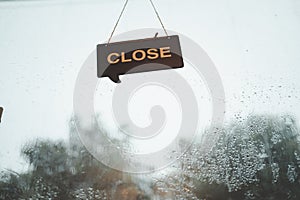 Close sign hanging on door at the cafe during raining